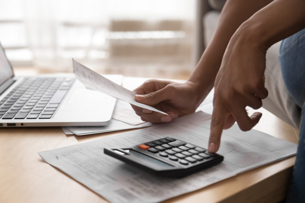 Person Holding Paper Bills and Using Calculator